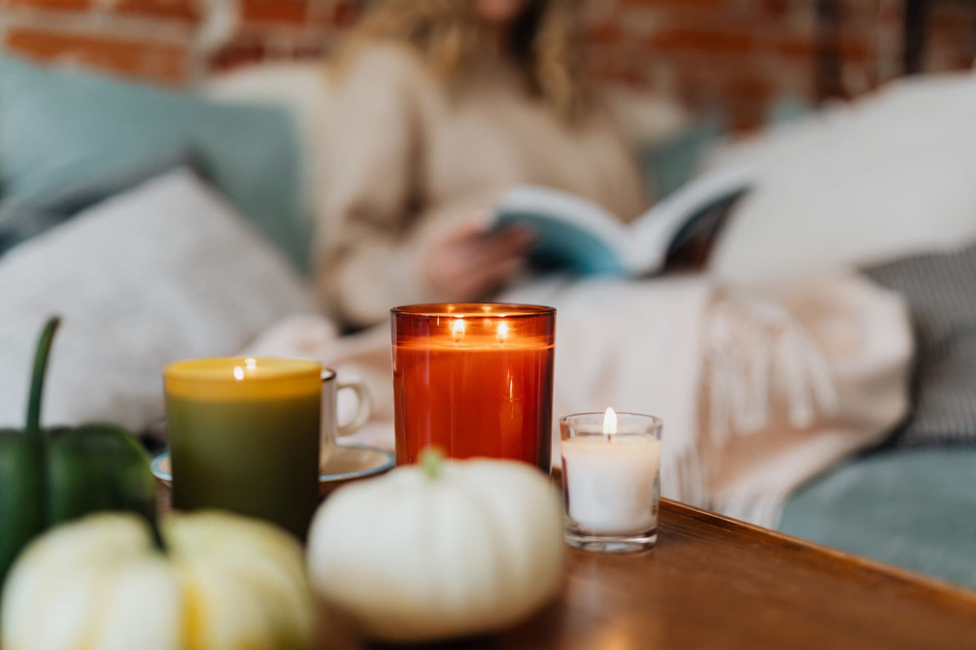 A reading corner with a lit candle and a mug beside a chair