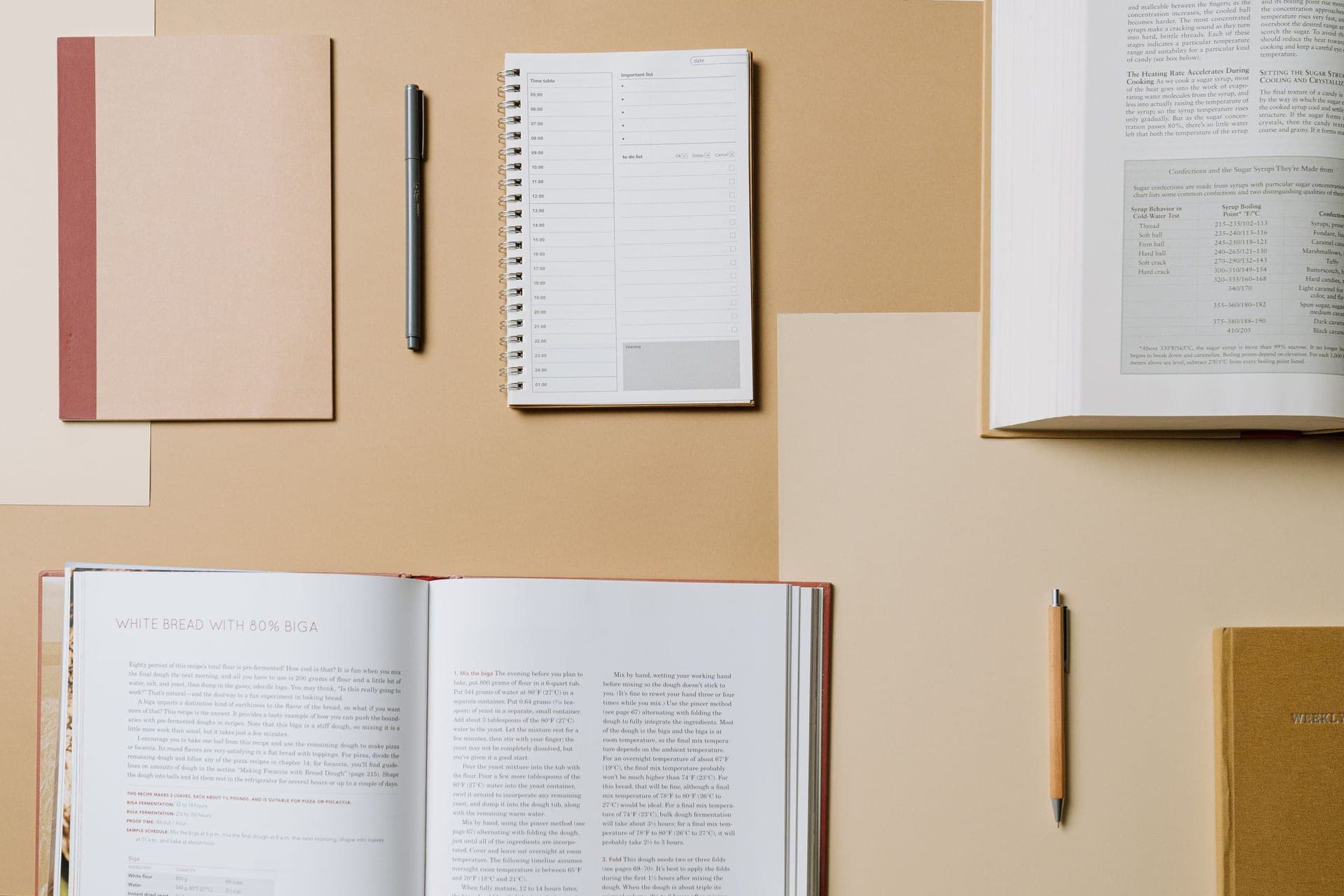 An open notebook and pen resting beside a closed book